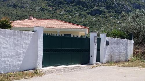 a green garage door in front of a house at Casa Das Oliveiras in Alvados