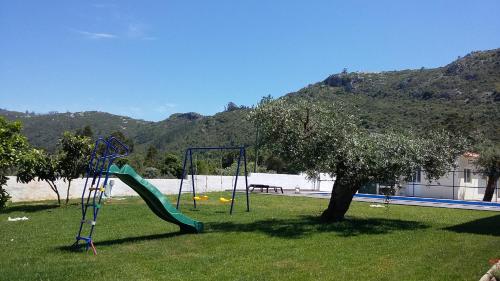 a playground with a slide in the grass at Casa Das Oliveiras in Alvados