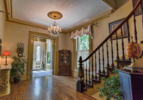 a hallway of a home with a staircase and a chandelier at The Woodview Inn in Gananoque