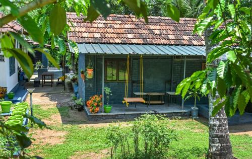 a green house with a porch with a swing at Rose Retreat Homestay in Kottayam