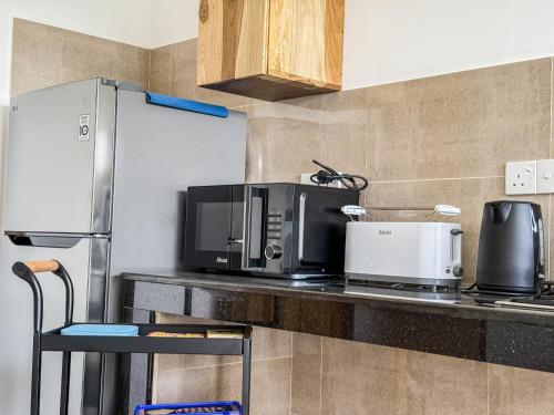 a kitchen counter with a microwave and a refrigerator at Gondolas Hotel Stay in Ragama