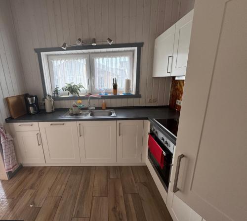 a kitchen with white cabinets and a sink and a window at Seeschwalbe 78 Kompassweg in Rechlin