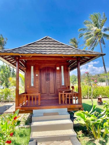 a wooden gazebo with a table and chairs at Golden Beach Hotel Sekotong in Pulau Gilipoh