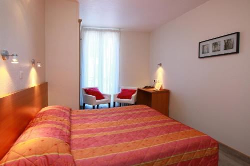 a hotel room with a bed and two chairs at Hôtel Panoramic in Luchon