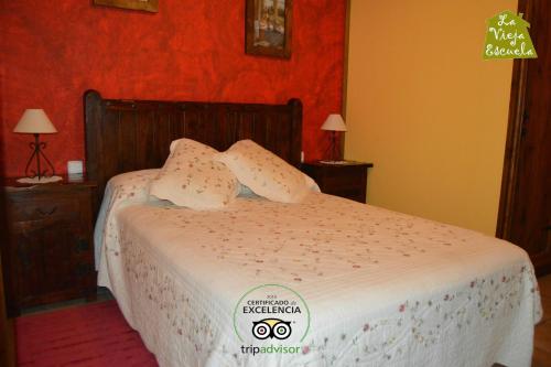 a bedroom with a bed with white sheets and red walls at Posada La Vieja Escuela in San Roque de Ríomiera
