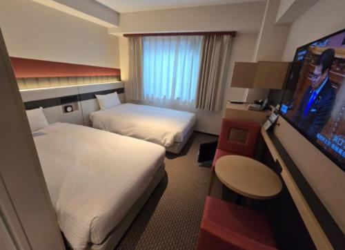 a hotel room with two beds and a flat screen tv at KIORI Exec Gojo in Kyoto