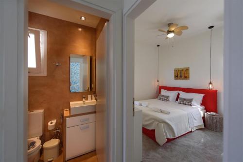 a bedroom with a bed with a red headboard and a bathroom at Lidia Beach Suites in Kokkinos Pirgos