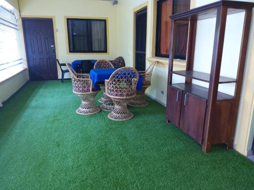a room with green carpet and chairs and a table at Residence Tropical Garden in Boca Chica