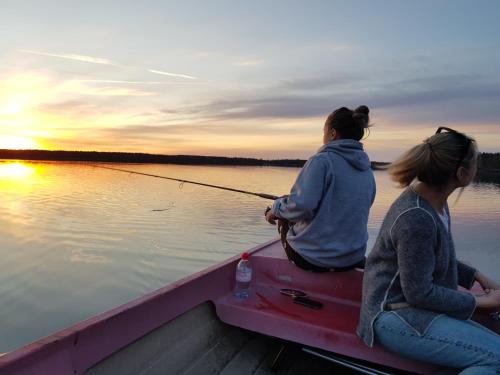 two women sitting on a boat with a fishing pole at Barnebo 3-6 in Blomstermåla
