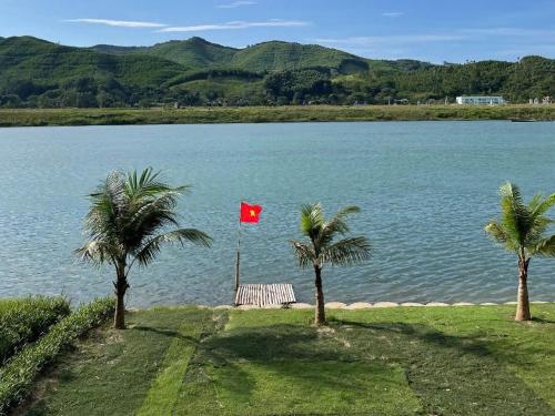 a red flag on a pole next to two palm trees at Village House in Phong Nha