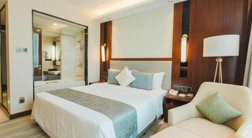a bedroom with a bed and a chair and a mirror at Grand Soluxe Zhongyou Hotel Shenzhen in Shenzhen