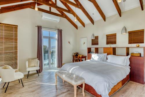 a bedroom with a large bed and a chair at Manor on the Bay in Gordonʼs Bay