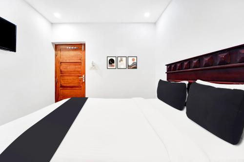 a bedroom with a large white bed and a wooden door at Hotel O Ernakulam Near North Railway Station in Cochin