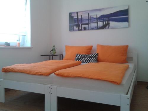 Bett mit orangefarbenen Kissen auf einem Zimmer in der Unterkunft Kleine Apartments in Torgau