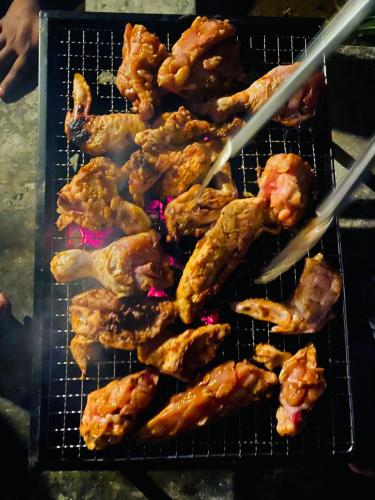 a grill with chicken wings and tongs cooking at The wilds Sinharaja in Deniyaya