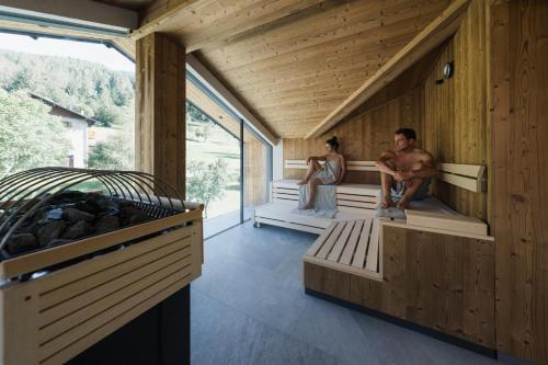 two people sitting on benches in a wooden room at Monroc Hotel in Commezzadura