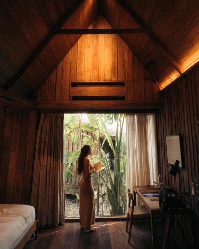a woman standing in front of a window in a room at The Asa Maia - Bespoke Wellness Resort in Uluwatu
