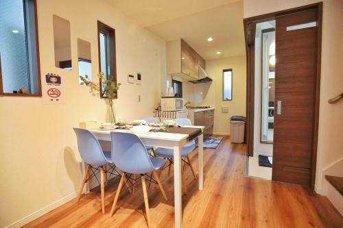 uma cozinha e sala de jantar com uma mesa e cadeiras brancas em SG5371 Visit Shibuya Crossing! Walking distance to a single family home for 8 people, private parking , downstairs supermarket food Shibuya em Tóquio