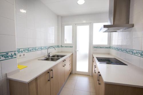a white kitchen with a sink and a window at Apartamentos Blanes-Condal Costa Brava in Blanes