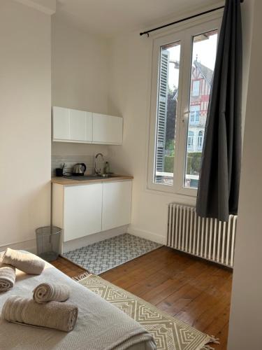 a white room with a bed and a kitchen at Chambre toute équipée in Lisieux