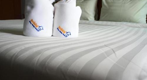 a white bed with white sheets and two pillows at Ritzy House Hotel in Chumphon