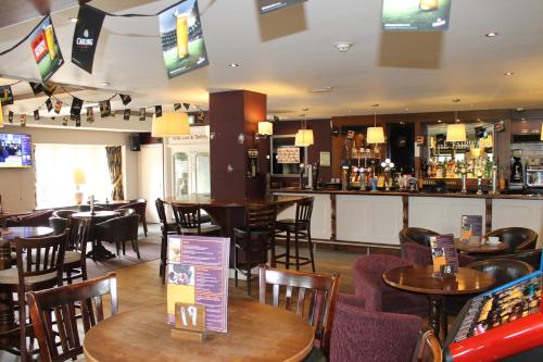 a restaurant with tables and chairs and a bar at The Fairways in Rotherham