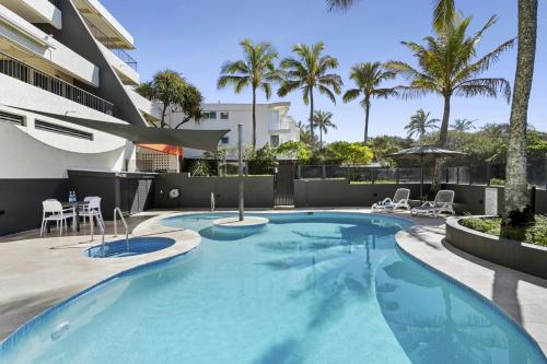 a swimming pool with chairs and a building at Costa Nova Holiday Apartments in Sunshine Beach