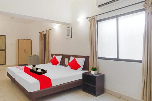 a bedroom with a bed with red pillows and a window at Hotel O Halcyon Inn in Candolim
