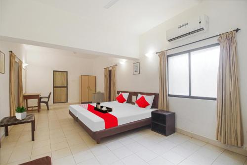 a bedroom with a bed with red pillows and a window at Hotel O Halcyon Inn in Candolim