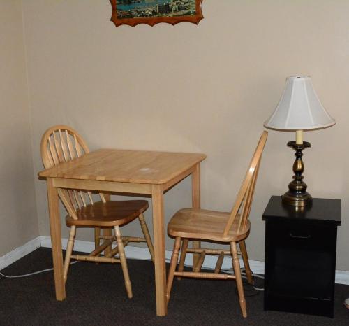 a wooden table with two chairs and a lamp at Bluebird Motel in Port Alberni