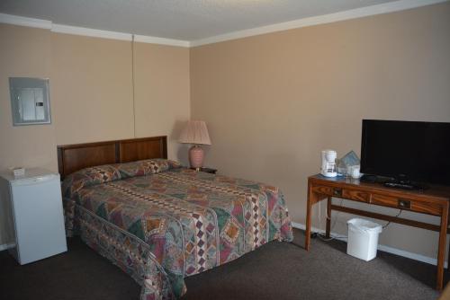 een slaapkamer met een bed en een bureau met een televisie bij Bluebird Motel in Port Alberni