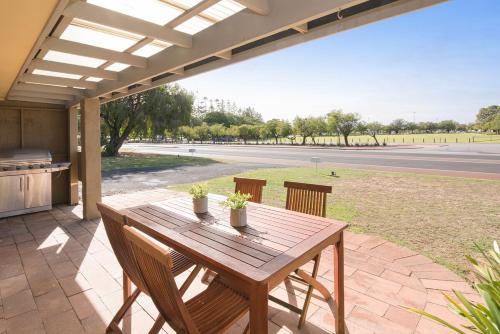 a wooden table and chairs on a patio at A Shore Thing- Located opposite Busselton Foreshore! in Busselton