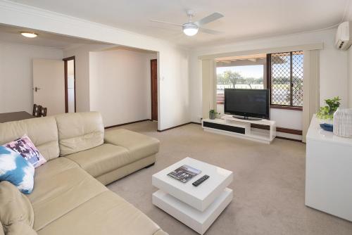 a living room with a couch and a tv at A Shore Thing- Located opposite Busselton Foreshore! in Busselton