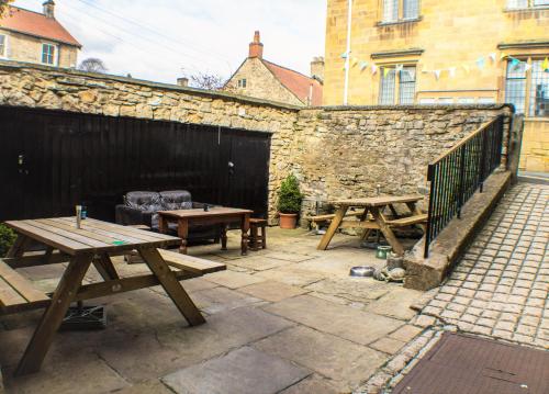 a patio with two picnic tables and a stone wall at The Royal Oak Hotel in Helmsley