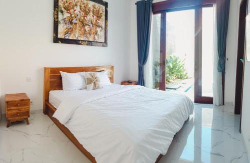 a bedroom with a large bed with white sheets at Pondok Talavana in Badung
