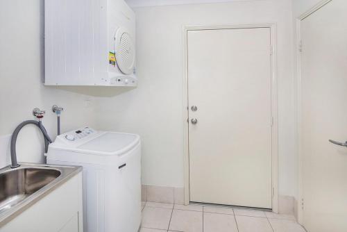 a white bathroom with a sink and a washing machine at Waters Edge- Kayaks, private jetty, WIFI in Geographe