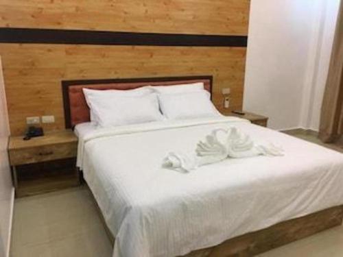 a large white bed with white sheets and pillows at Hotel Primera in Zamboanga