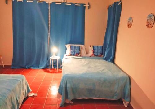 a bedroom with two beds and a blue curtain at Beachfront Serenity Villa with Pool, AC, 1 min from the the beach, Jacuzzi, Wifi in Sabana Grande de Palenque