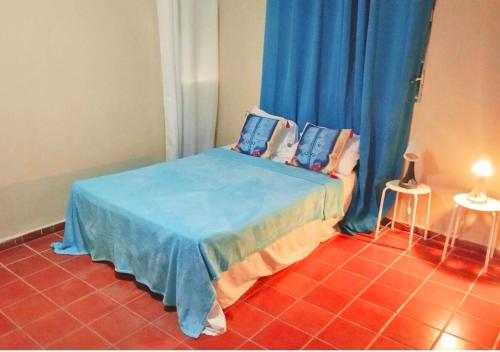 a bedroom with a bed with blue sheets and blue curtains at Beachfront Serenity Villa with Pool, AC, 1 min from the the beach, Jacuzzi, Wifi in Sabana Grande de Palenque