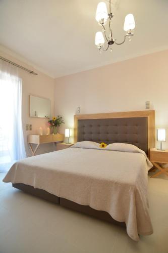 a white bedroom with a large bed and a chandelier at Ilioxenia Chios Studios & Apartments in Paralia Agias Foteinis
