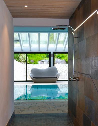 La salle de bains est pourvue d'une douche en verre et d'une baignoire. dans l'établissement Les Gentianettes Hotel & Spa, à La Chapelle-dʼAbondance