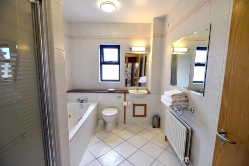 a bathroom with a tub and a toilet and a sink at Cromore Halt in Portstewart