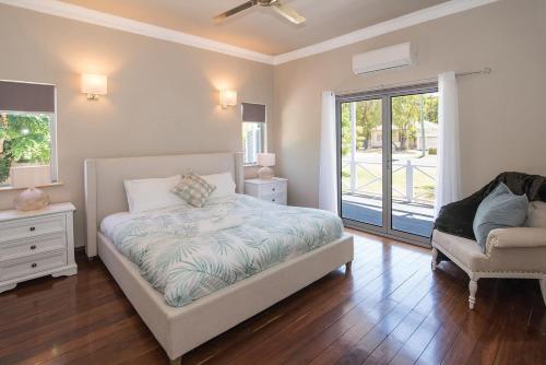 een slaapkamer met een bed, een stoel en een raam bij All Decked Out- WIFI, AC in bedrooms, Fireplace in Busselton