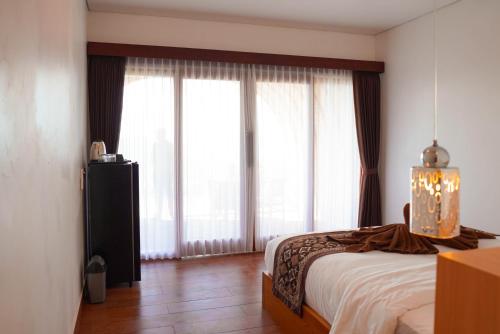 a bedroom with a bed and large windows at Pinggan Skyline in Baturaja