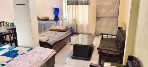 a room with two beds and a table and chairs at श्री जी निकुंज in Chhatikara