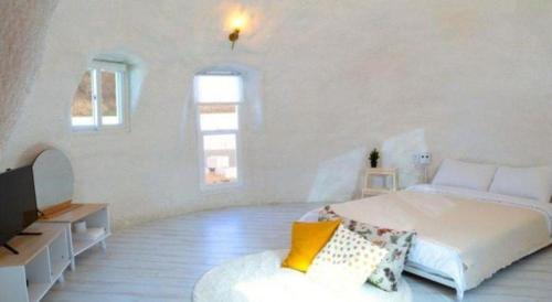 a white bedroom with a bed and a tv at All That Water Pension in Gapyeong