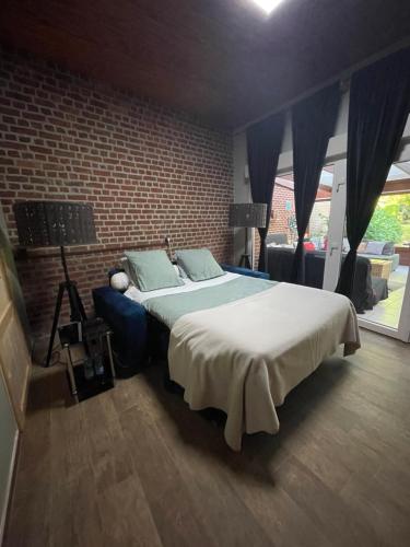 a bedroom with a large bed and a brick wall at Havre de paix in Maizières