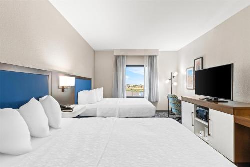 a hotel room with two beds and a flat screen tv at Hampton Inn Laramie in Laramie