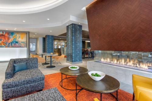 a lobby with a fireplace and a chair and tables at Cambria Hotel Downtown-Center City in Philadelphia