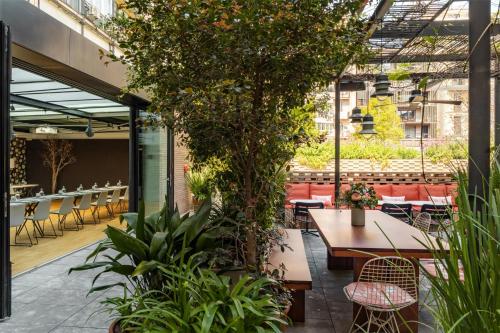 a patio with tables and chairs and plants at Alexandra Barcelona Hotel, Curio Collection by Hilton in Barcelona